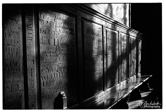 Black and white photography of a wall full os carved signatures. From Harrow School London. 